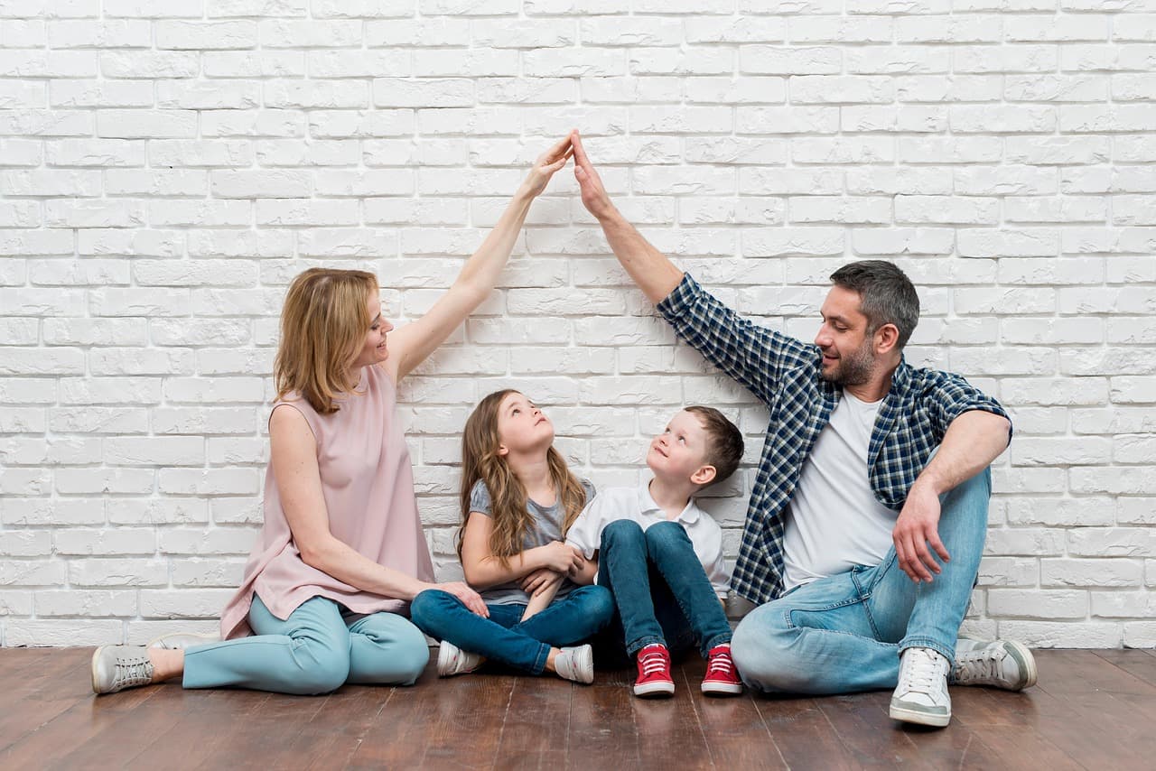 Parents framing a roof shape over their children — the feeling of home