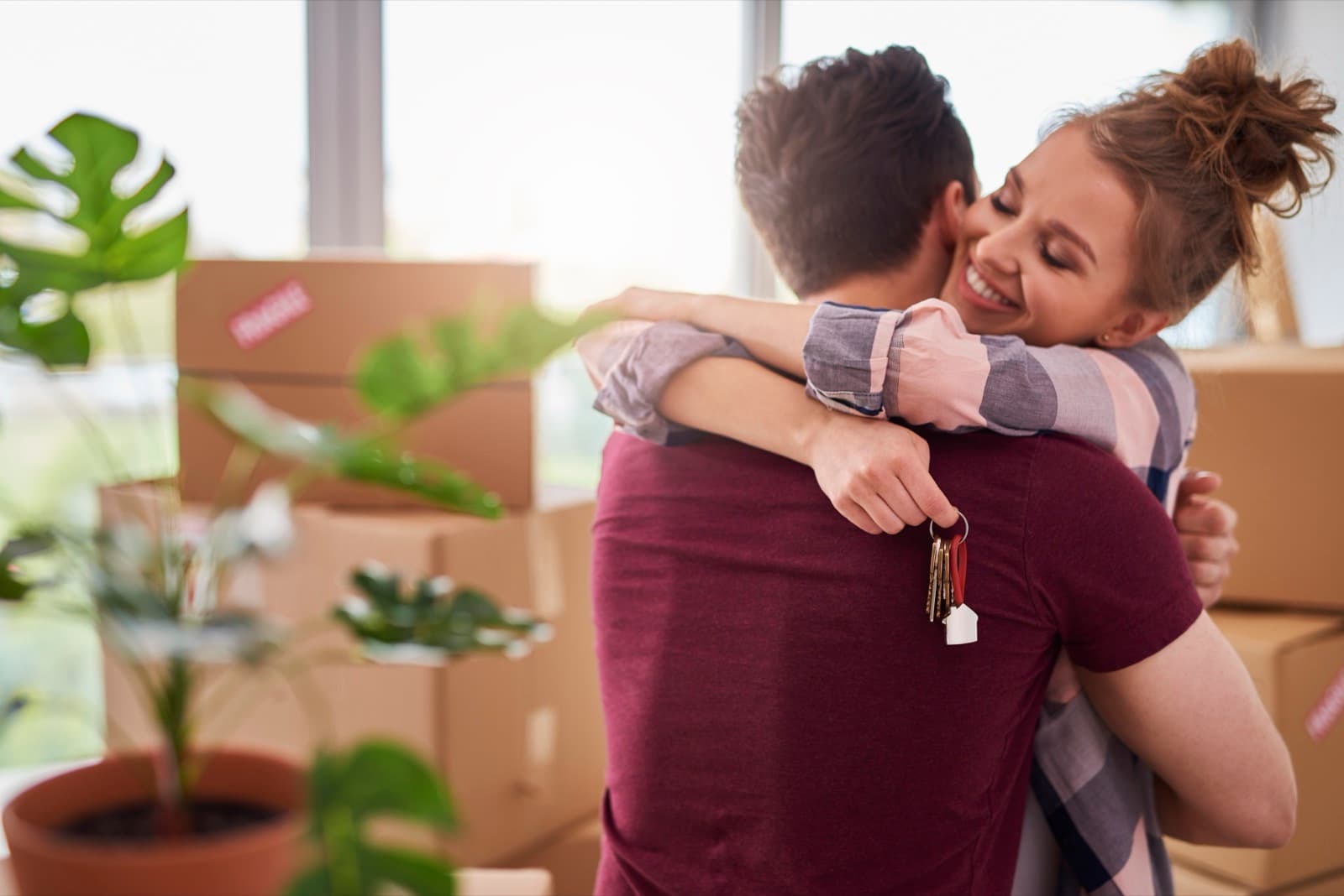 New homeowners embracing while holding the keys to their home