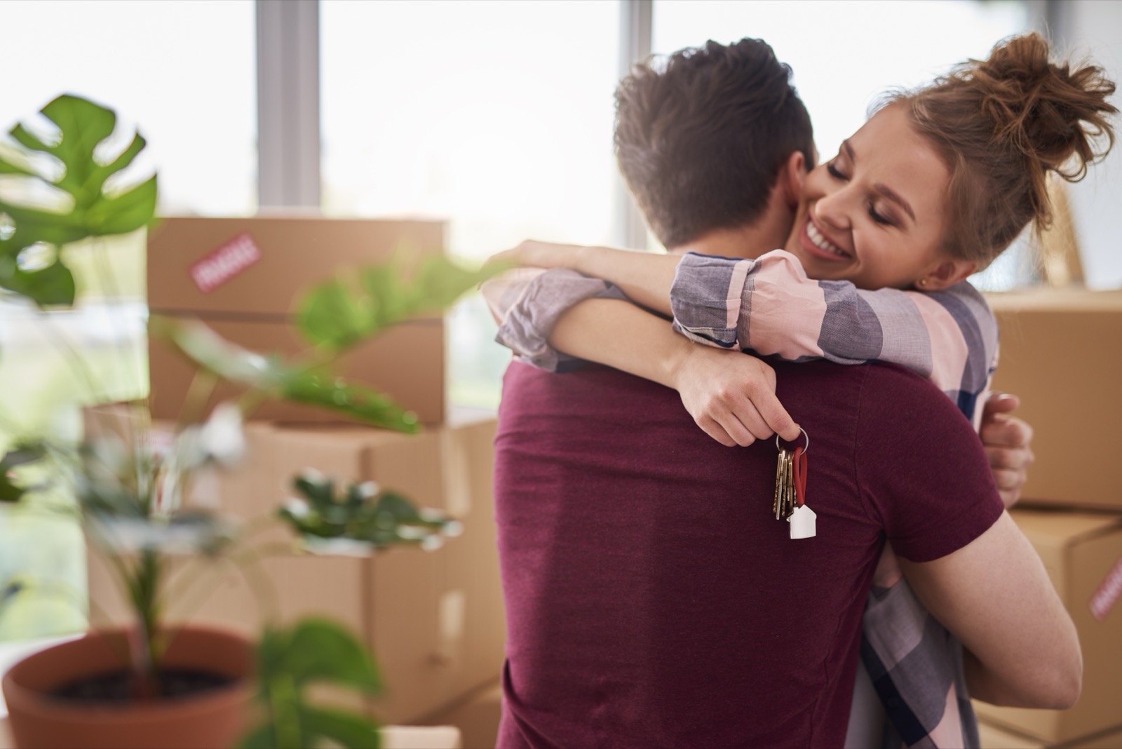 New homeowners embracing while holding the keys to their home